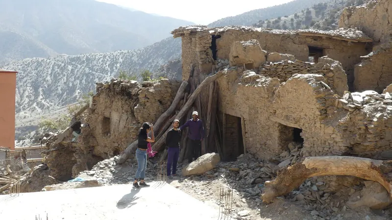 Earthquake-damaged stone houses on a snow-dusted High Atlas Mountains hillside